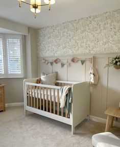 a baby's room with a white crib and wallpaper on the walls