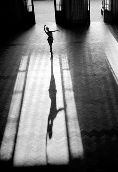 a person standing in an empty room with their arms out and shadow on the floor