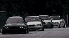 a group of cars parked next to each other on the side of a road with trees in the background