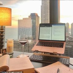 an open laptop computer sitting on top of a desk next to a glass of wine