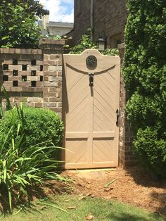 a gate with a clock on it in the middle of a yard next to some bushes