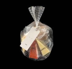 a clear plastic bag filled with assorted cheeses on top of a black background