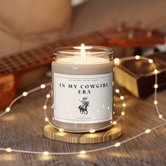 a candle sitting on top of a table next to a string of lights and a guitar