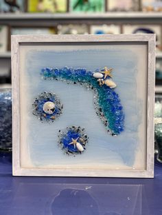 a blue and white frame with three seashells on it