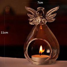 a clear glass angel candle holder with a lit candle in the middle and measurements for it