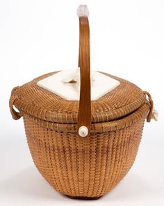 a wicker basket with a white cloth in the top and handle on it, sitting against a white background