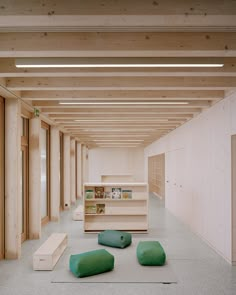 an empty room with green bean bags and bookshelves on the floor in front of it