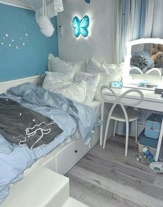 a bedroom with blue walls, white furniture and a butterfly shaped mirror on the wall