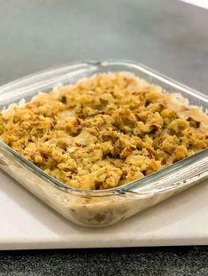 a casserole dish filled with stuffing on top of a white counter next to a knife