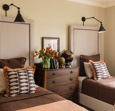 two beds in a bedroom with brown and white bedding, one has flowers on the nightstand