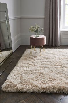 a living room with a white rug and mirror