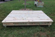 a wooden pallet sitting in the grass next to a tree and flower potted plant