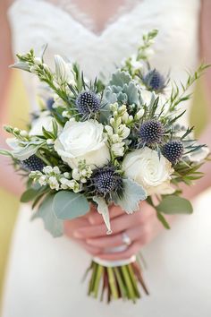 a bride holding a bouquet of white and blue flowers