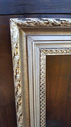 an ornate gold and white frame on a wooden wall