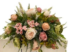 a bunch of flowers that are on top of a white box with greenery around it