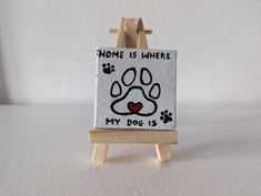 a miniature easel with a dog's paw print on it and the words home is where my dog is