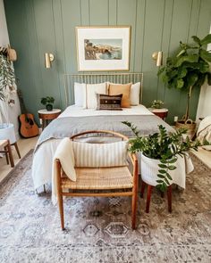 a bedroom with a bed, chair and potted plants on the floor in front of it