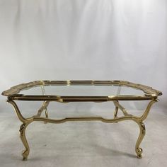 a coffee table with glass top and gold metal frame, sitting on a white background