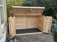 a large wooden storage box sitting on top of a brick walkway