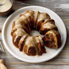 a bundt cake with icing on a plate next to a glass of milk