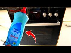 a hand holding a bottle of dish soap in front of an oven