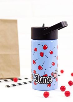 a blue water bottle with the word june on it and cherries scattered around it