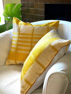 two yellow and white pillows sitting on top of a couch