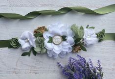 two white flowers and green ribbons on a table