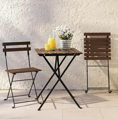 two wooden chairs sitting next to each other near a small table with drinks on it