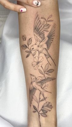 a woman's leg with a bird and flower tattoo on the left side of her arm