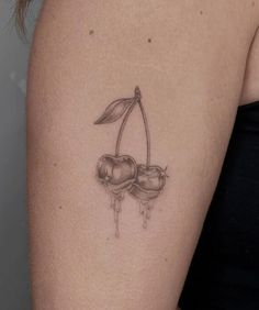 a woman's arm with two cherries and a leaf tattoo on the side