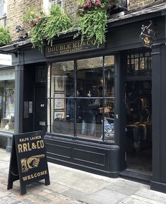 the outside of a store with plants growing out of it's windows and signage