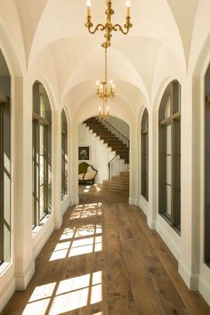 the hallway is lined with arched windows and wooden floors, along with chandeliers