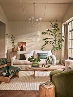 a living room filled with lots of furniture next to a large window and potted plant