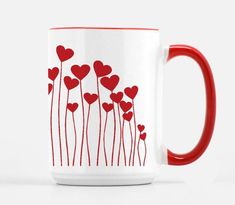 a red and white coffee mug with hearts on the inside is sitting in front of a white background