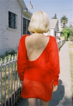 the back of a woman's body is visible as she walks down a sidewalk