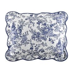 a blue and white pillow with flowers on the front, sitting on a white surface