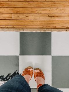 a person standing in front of a tiled floor with their feet propped up on the ground