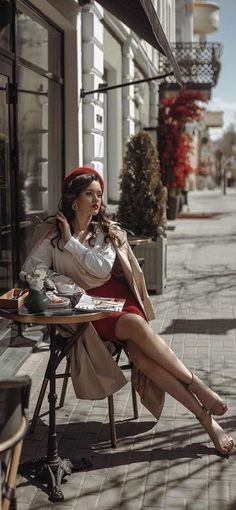 a woman sitting at a table with food in front of her on the street side