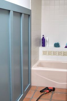 a bathroom with blue and white tile on the floor next to a bathtub, shower head, and tools