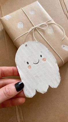 a hand holding a piece of paper with a face on it and a gift wrapped in brown paper