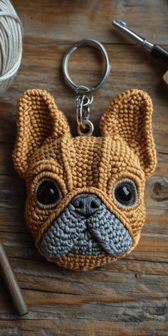 a crocheted keychain with a dog's face is shown on a wooden surface