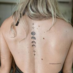 the back of a woman's neck with three moon tattoos on her left side