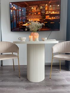 a dining room table with two chairs and a painting on the wall in the background