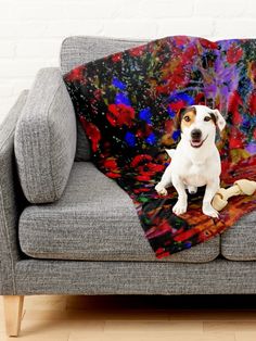 a dog sitting on top of a couch under a blanket