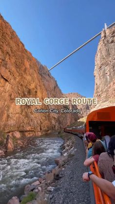 people are riding on an orange tour bus near a river and rocky mountain side, with the words royal gorge route written above it