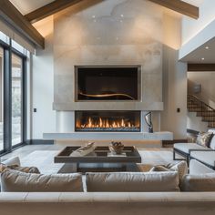 a living room with couches and a fire place in the center, surrounded by windows