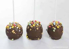 three cake pops with chocolate frosting and sprinkles on them, sitting side by side