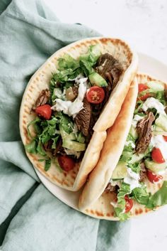 two pita breads filled with meat, lettuce and tomatoes on a plate