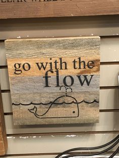 a wooden sign that says go with the flow on it and an image of a boat